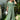 Embroidered green lace maxi dress in a bohemian style, featuring intricate patterns and a flowing design. The dress is presented as formal wear, suitable for summer events, with a focus on the shoulder and waist areas.