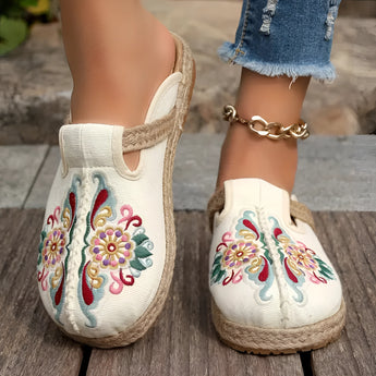 Pair of slip-on espadrilles with embroidered pink floral design, worn on a person's feet, showcasing boho chic style.