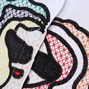 Colorful geometric streetwear hoodie with snap buttons, featuring intricate embroidery designs, worn by a person with black hair.