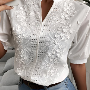 Embroidered white floral lace blouse with short sleeves and eyelet detailing, featuring a round neckline and fitted waist.