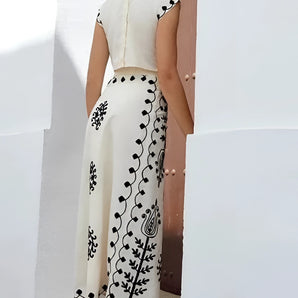 A woman wearing an embroidered white linen midi dress, featuring a sleeveless design suitable for summer. The dress has a fitted waistline and falls to knee-length, embodying a casual yet stylish day dress look.