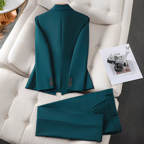 Emerald green peplum blazer suit featuring tailored sleeves and a structured collar, displayed against a backdrop of a white wall with a decorative houseplant.