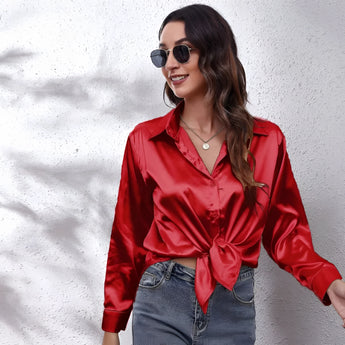
A person wearing an emerald green satin long sleeve button-down blouse, showcasing the blouse's elegant sheen and button detailing.