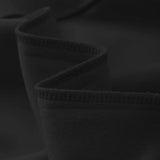 A black crewneck sweater displayed in a monochromatic setting, folded neatly on a table with minimalistic décor, highlighting its classic and casual knit design.
