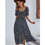Woman wearing a marine blue floral boho maxi dress with puff sleeves and a high slit, showcasing a relaxed and happy demeanor.