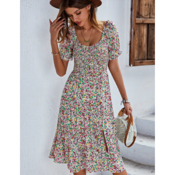 Woman wearing a beige floral boho maxi dress with puff sleeves and a high slit, posing with one hand on her waist.