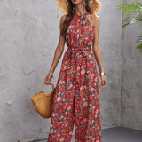 Floral halter neck jumpsuit featuring a tropical bohemian design, styled for women's beachwear with emphasis on the neckline and sleeveless cut, showcasing a fitted waist and flowing thigh-length pants.