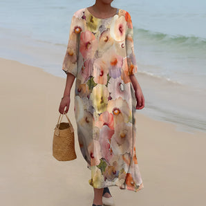 Floral maxi chiffon beach dress featuring a boho chic design, perfect for resort wear, worn by a woman standing on a beach with a scenic water backdrop. The dress is lightweight with a flowing design, showcasing a stylish neckline and sleeves, complemented by sunglasses.