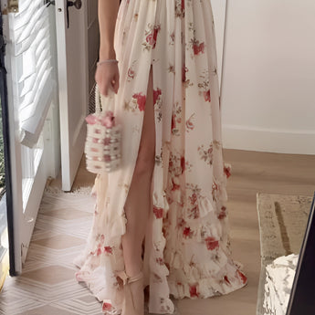 Floral pink maxi dress with a slit, featuring a fitted waist, short sleeves, and a round neckline, designed for a summer garden party setting.