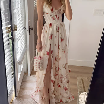 White floral maxi dress with slit and short sleeves, displayed in an XL size, featuring delicate floral patterns. The dress has a fitted waist and elegant design suitable for a summer garden party. The background includes a window and a door, suggesting an indoor setting.