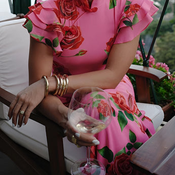 Pink ruffle gown featuring a floral mermaid design, perfect for garden parties, with a model smiling and wearing a necklace, surrounded by greenery.