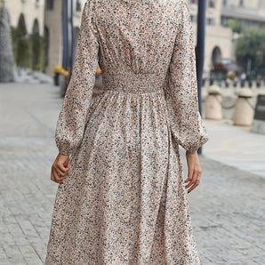 Woman wearing a floral midi dress with long sleeves, high-neck, and gathered waist, showcasing fall fashion.