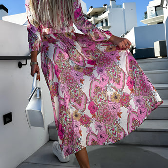 Pink floral midi dress with paisley pattern, featuring long sleeves and a fitted waist, ideal for spring fashion.