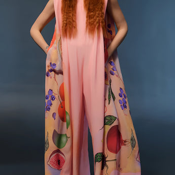 
A woman wearing a floral peach sleeveless jumpsuit, showcasing elegant summer fashion. The jumpsuit features a fitted waist and a comfortable one-piece design, suitable for warm weather.