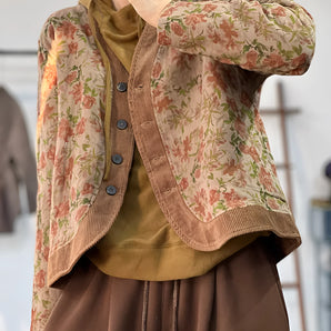 Floral print cardigan with ribbed trim featuring pink and plaid patterns, showcasing a wrap style with a collar and long sleeves.