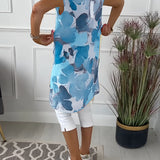 Woman wearing a floral print sleeveless summer tunic top with blue accents, standing confidently.