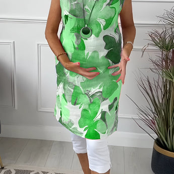 A woman wearing a floral print sleeveless summer tunic top with a vibrant design, featuring a scoop neck and flowy silhouette, standing outdoors.