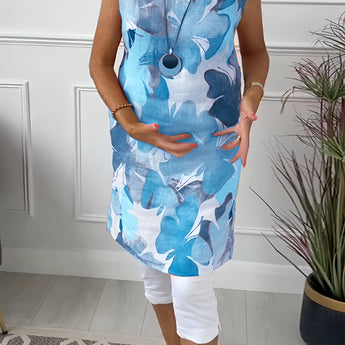 Floral print sleeveless summer tunic top for women, featuring a blue and white floral design, shown on a mannequin with visible shoulder and neck details.