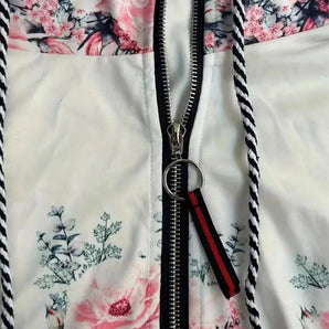 Floral print women's jacket featuring decorative zipper, with long sleeves and a collared neckline.