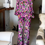 
A purple and black floral print women's off-shoulder jumpsuit designed for luxury evening wear, featuring long sleeves and an elegant neckline in size XL.