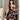 Elegant black floral strapless mini dress, perfect for parties, showcasing a one-piece design with a fitted waist, sleeveless cut, and a short hemline. Model has styled hair and is posing to highlight the shoulder, arm, and leg features of the dress.