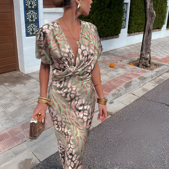 Olive green maxi dress with a floral pattern, featuring a V-neckline and puff sleeves, draped elegantly on a mannequin.