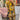 Yellow floral V-neck summer dress for women in mustard yellow color, featuring a casual and fashionable design, displayed on a mannequin with a hat and sunglasses, emphasizing the short sleeves and fitted waist.