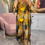 Floral V-neck yellow summer dress for women displayed on a mannequin in a stylish indoor setting, surrounded by modern furniture, including a chair and a couch, with a plant adding a touch of greenery.