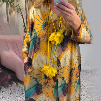 A vibrant yellow floral V-neck summer dress for women, featuring short sleeves and a casual fit, styled with a matching bag and sunglasses.