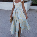 Floral vintage summer dress with sleeves in pastel blue and yellow, worn by a person. The dress is a one-piece garment featuring a fitted shoulder and flowing knee-length skirt, suitable for daytime wear. The model has visible arms and legs, and the dress is styled for an elegant and classic look.