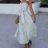 Floral vintage summer dress with sleeves in pastel blue and yellow, featuring a fitted waist and flowing skirt, modeled by a woman with visible shoulders and arms.