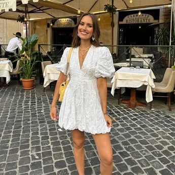 Floral white puff sleeve V-neck short summer dress worn by a woman standing and smiling, highlighting the dress's elegant one-piece design with emphasis on the sleeves and waist.