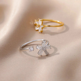 A hand wearing a flower-shaped diamond gold floral engagement ring, showcasing elegant botanical jewelry design.