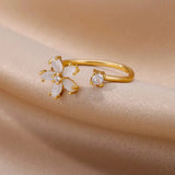 A gold engagement ring designed in the shape of a flower, featuring a central diamond and elegant botanical details.