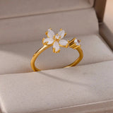Elegant botanical engagement ring with a flower-shaped diamond set in gold, displayed on a finger.