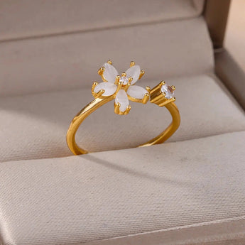 Elegant botanical engagement ring with a flower-shaped diamond set in gold, displayed on a finger.