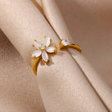 A hand wearing an elegant botanical engagement ring with a flower-shaped diamond set in gold, showcasing delicate petal details.