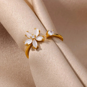A hand wearing an elegant botanical engagement ring with a flower-shaped diamond set in gold, showcasing delicate petal details.