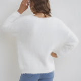 Woman wearing a fluffy white V-neck sweater with long sleeves, showcasing soft and cozy winter wear.