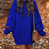 
A woman wearing a forest green oversized cable knit sweater dress with a cozy turtleneck.