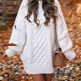 
A woman wearing a white, oversized cable knit sweater dress with a cozy turtleneck, showcasing a relaxed and stylish look.