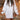 
A woman wearing a white, oversized cable knit sweater dress with a cozy turtleneck, showcasing a relaxed and stylish look.