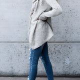 A woman wearing a fringed gray Bohemian wool cowl neck sweater with long sleeves and chic winter knitwear style.