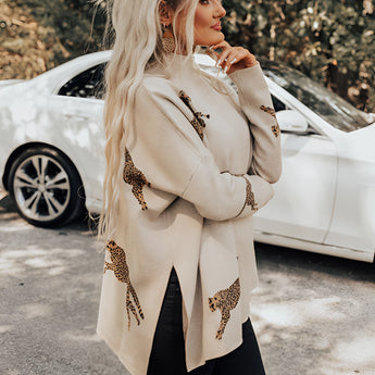 A person wearing a fuchsia ethnic pattern sweater with boho chic embroidery, standing outdoors. The sweater features intricate designs and long sleeves, styled casually with hair down. A parked car is visible in the background.
