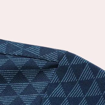 Men's polo shirt featuring a geometric blue triangle pattern with a tartan and plaid design, showcasing shades of azure and electric blue. The shirt has short sleeves and a casual yet stylish appearance, ideal for a modern and fashionable look.