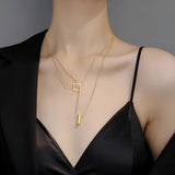 Elegant minimalist necklace with geometric gold bar and square pendants displayed on a model wearing a lingerie top.