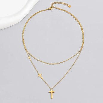 Gold cross pendant necklace featuring a minimalist design, layered on an adjustable chain, made from natural materials and metal, suitable as Christian jewelry or fashion accessory.