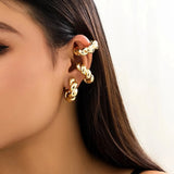 Gold diamond-studded hoop earrings with a twisted glossy finish, worn on a woman's ear.