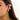 Gold diamond-studded hoop earrings with a twisted glossy finish, worn on a woman's ear.