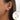 Gold diamond-studded hoop earrings with a textured polished finish worn by a woman.